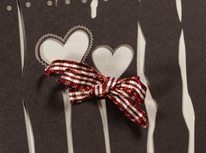 Vergrößerte Abbildung Zwei Herzen mit angeknüpfter, rot-weiß karierter Trachtenschleife.